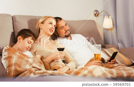 Happy family with sleeping son watching tv 39569701