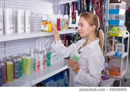 Female shop assistant offering shampoo Female shop assistant offering shampoo 39569865