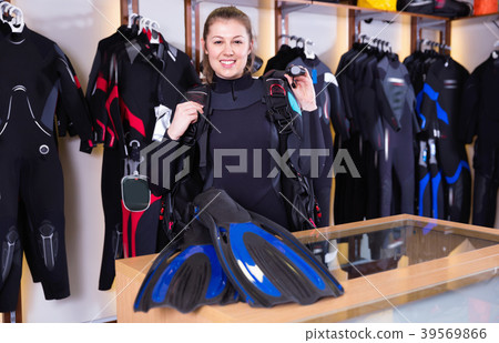 Sporty woman is satisfied of full set diving equipment in the diving store. 39569866