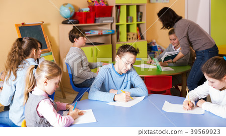 Kids studying and teacher helping Kids studying and teacher helping 39569923