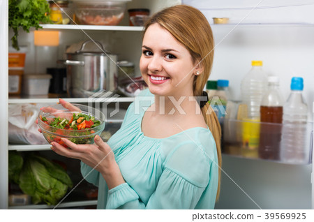 long-haired woman arranging space in fridge at home long-haired woman arranging space in fridge at home 39569925