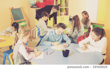 boys and girls sitting and teacher helping drawing boys and girls sitting and teacher helping drawing 39569926