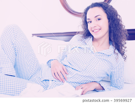 Brunette female lounging in bed and smiling 39569927