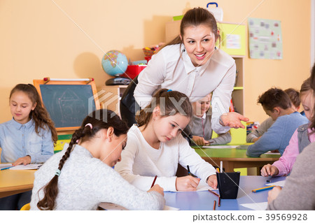 Group of school kids with pens and notebooks studying in classroom with teacher 39569928