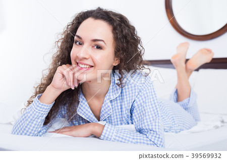 Brunette female lounging in bed and smiling Brunette female lounging in bed and smiling 39569932