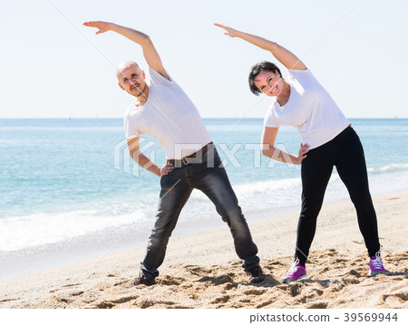 man and woman exercising together on the beach man and woman exercising together on the beach 39569944