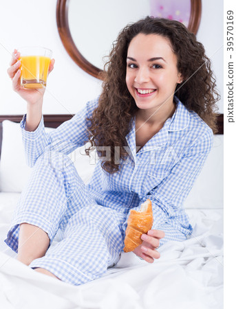 Adult girl eating pastry and juice in bed Adult girl eating pastry and juice in bed 39570169