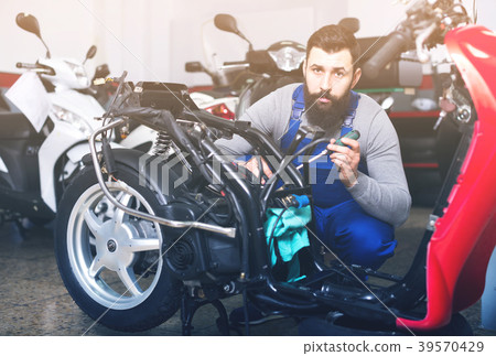 Young male worker working at restoring motorbike in workshop 39570429
