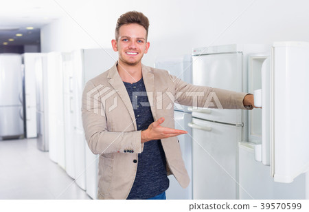 Ordinary male customer looking at modern fridges 39570599