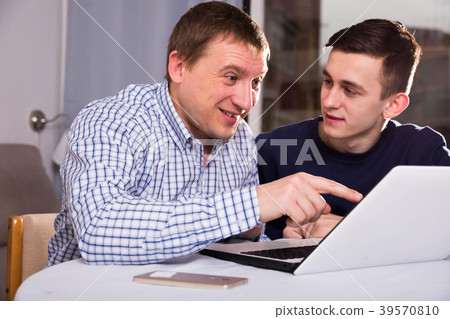 Guy with his father are resting and looking in notebook 39570810