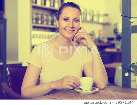 young cheerful woman resting alone in cafe and drinking coffee 39571144