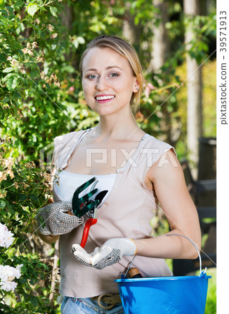 Glad woman having horticultural instruments in garden 39571913