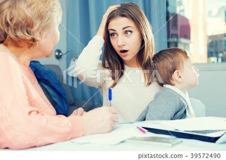 Puzzled aged woman is mastering technology near laptop with her daughter and grandson 39572490