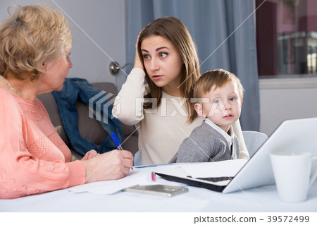Two women are puzzled of problems with filling utility bills with laptop Two women are puzzled of problems with filling utility bills with laptop 39572499