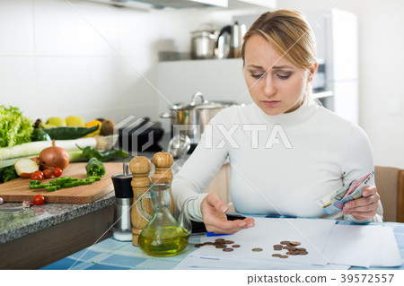 Broke woman with money and bills in kitchen Broke woman with money and bills in kitchen 39572557
