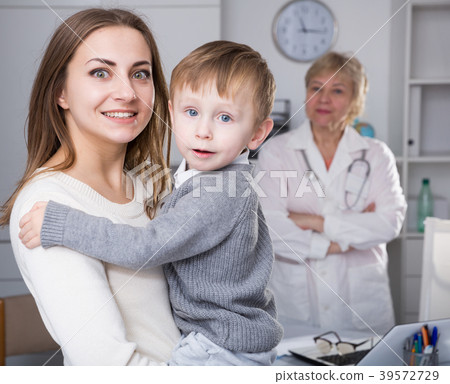 Smiling female is standing satisfied with her toddler after visiting clinic 39572729