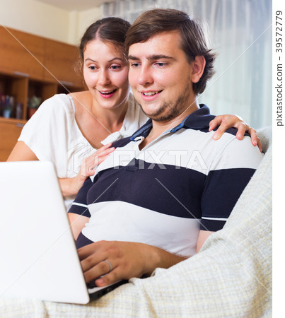 Happy couple with laptop at home. 39572779
