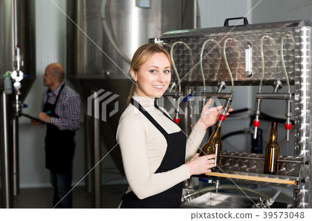 Smiling female brewery worker with bottling machinery 39573048