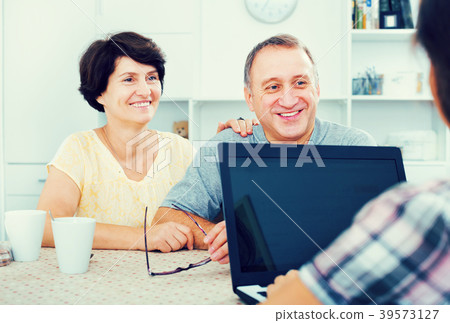 Mature couple looking at woman showing laptop Mature couple looking at woman showing laptop 39573127