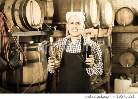 Happy mature man working on cork bottle device Happy mature man working on cork bottle device 39573151