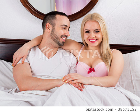 Beautiful positive young couple posing in family bed Beautiful positive young couple posing in family bed 39573152