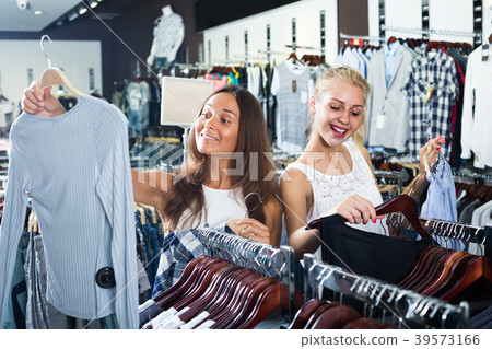two girls buying tops in clothes store . 39573166