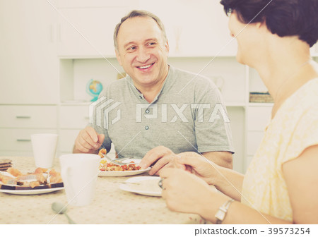 Mature man eating lunch and listening to woman Mature man eating lunch and listening to woman 39573254