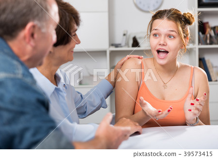 Smiling woman is talking with her parents at the table 39573415
