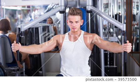 vigorous young man training upper body using fly machine vigorous young man training upper body using fly machine 39573500