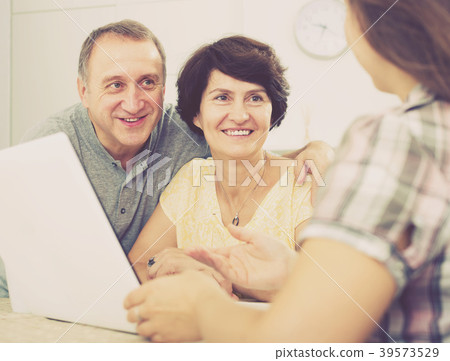 Adult couple listening to woman with laptop Adult couple listening to woman with laptop 39573529