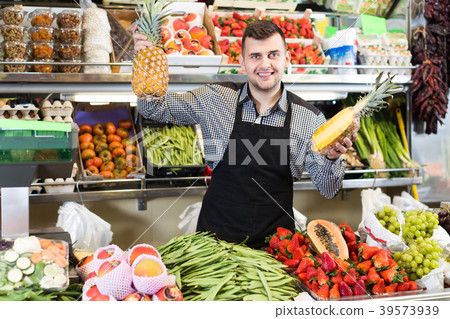 active male seller showing assortment of grocery shop 39573939