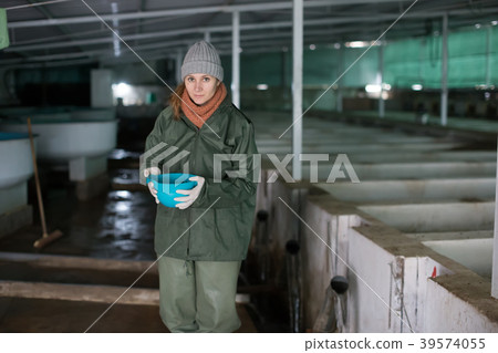 Woman feeding fish in tanks on farm Woman feeding fish in tanks on farm 39574055