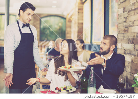 Adult couple expressing dissatisfaction with waiter about food Adult couple expressing dissatisfaction with waiter about food 39574197