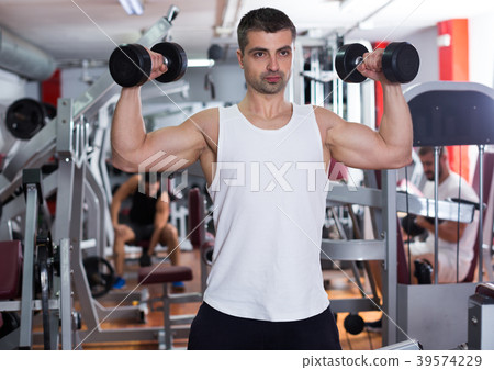 Man exercising with dumbbells in gym Man exercising with dumbbells in gym 39574229