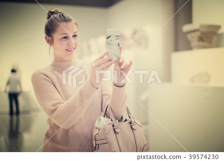 Positive female holding mobile in the historical museum 39574230