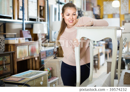 Positive woman customer touching dressing table in furniture shopping room Positive woman customer touching dressing table in furniture shopping room 39574232