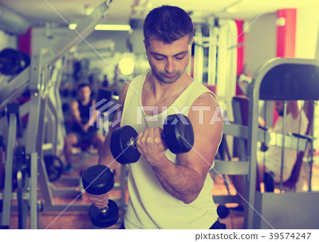 Man doing exercises with dumbbells at gym 39574247