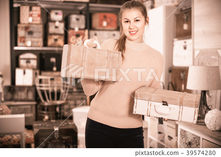 cheerful woman buyer holding wooden suitcase in furniture shopping room cheerful woman buyer holding wooden suitcase in furniture shopping room 39574280