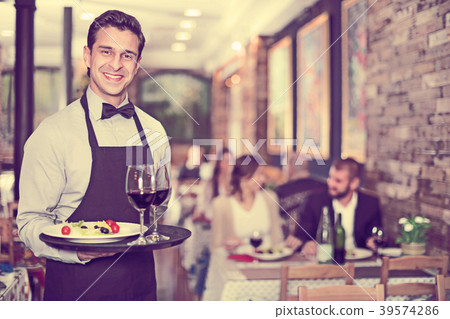 Smiling waiter with serving tray in restaurant Smiling waiter with serving tray in restaurant 39574286