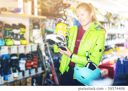 Customer woman in ski equipment is choosing boots Customer woman in ski equipment is choosing boots 39574406