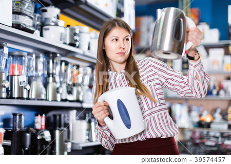 Young attractive woman choosing kettle in household appliances store Young attractive woman choosing kettle in household appliances store 39574457