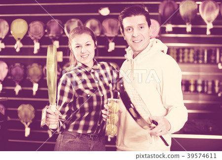 Sporty couple is demonstraiting modern racket and balls for padel 39574611