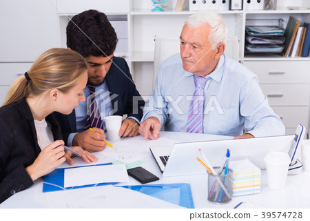 Employees are writing financial reports and discussing with mature boss Employees are writing financial reports and discussing with mature boss 39574728