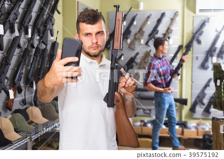 Male is taking selfie on phone with air gun 39575192