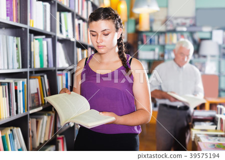 Young woman is choosing novel for buying Young woman is choosing novel for buying 39575194