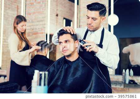 Hairdresser man doing styling of guy with electric hair clipper 39575861