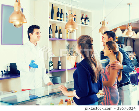 Hospitable pastryman serving positive visitors Hospitable pastryman serving positive visitors 39576024