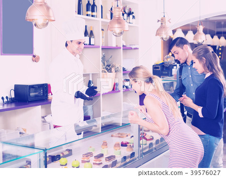 Male baker is offering delicious cakes from showcase Male baker is offering delicious cakes from showcase 39576027