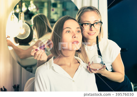 Woman makeup artist applying cosmetics for female Woman makeup artist applying cosmetics for female 39576030