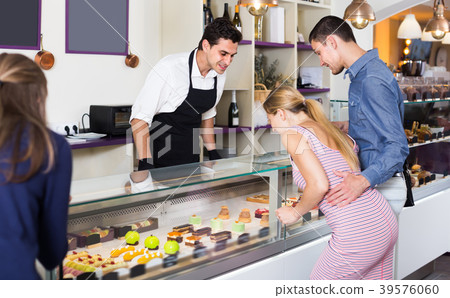 Smiling seller helping friends to choose sweets Smiling seller helping friends to choose sweets 39576060